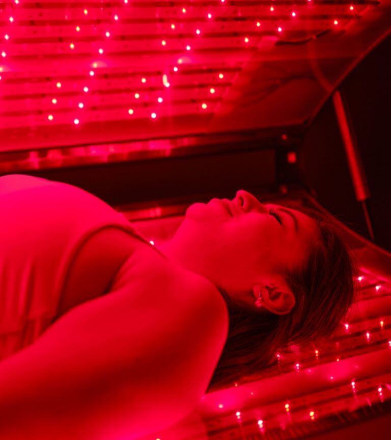 Woman lying in a red light therapy bed at Gold’s Gym Cheyenne using recovery and wellness technology